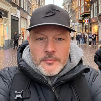 Tripp Brower in a dark cap and padded winter jacket on a busy city shopping street
