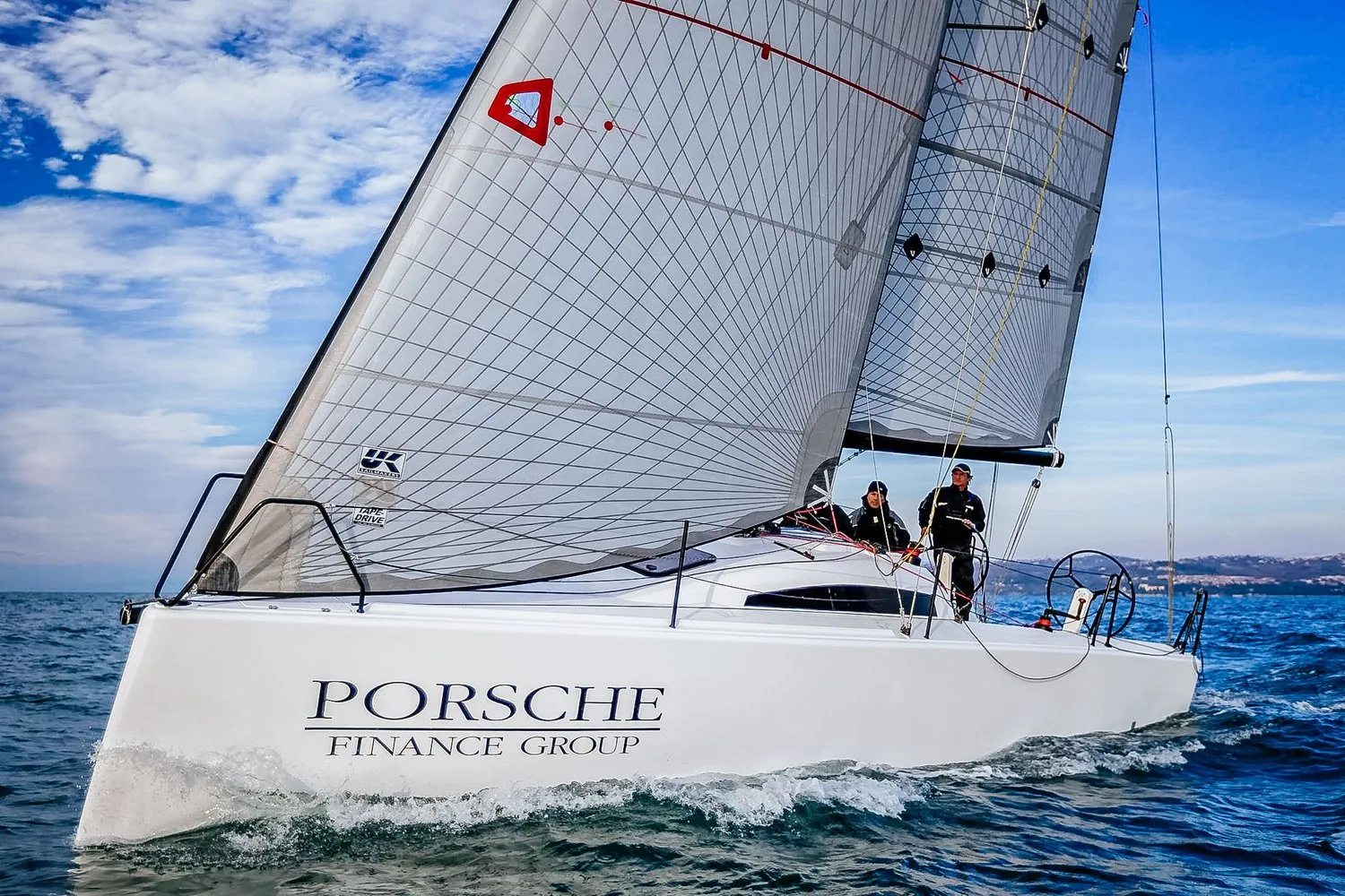 Luka 30 with Porsche Finance Group hull lettering sailing upwind under grey UK Sailmakers laminate sails