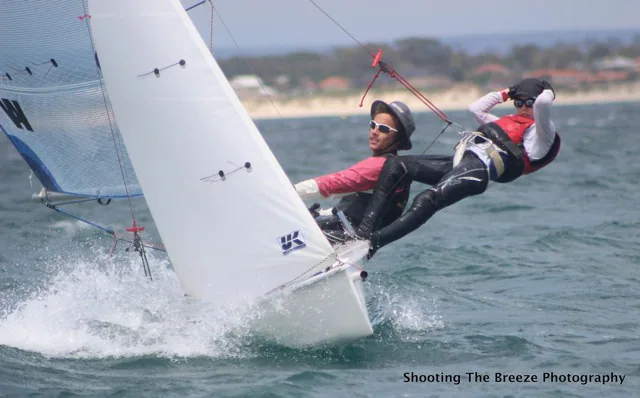 Two young sailors hiking a Flying Ant dinghy hard, crew stretched out over the water, UK Sailmakers logo on the main