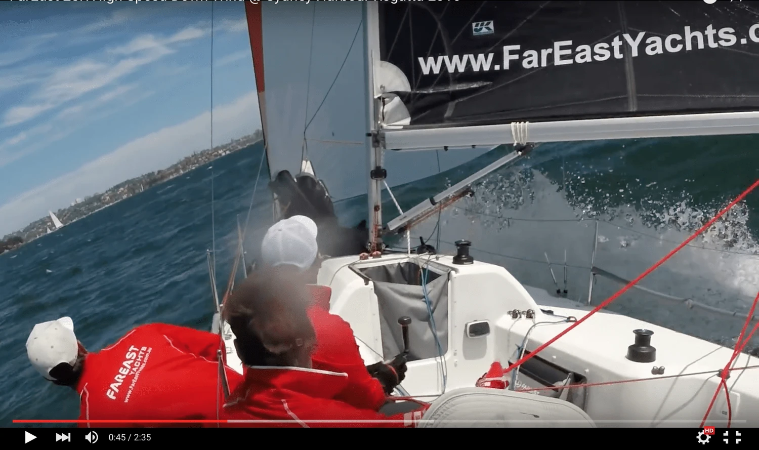 Video still aboard a FarEast 28R: crew in red FarEast jackets, spray flying, FarEast Yachts banner on the sail