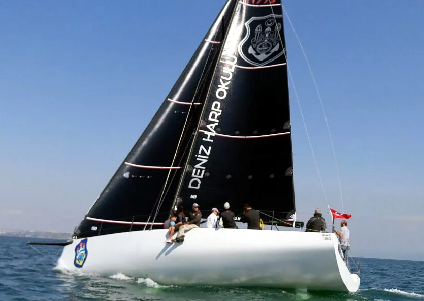 Turkish Navy yacht under a black Uni-Titanium mainsail lettered DENIZ HARP OKULU, crew on the rail