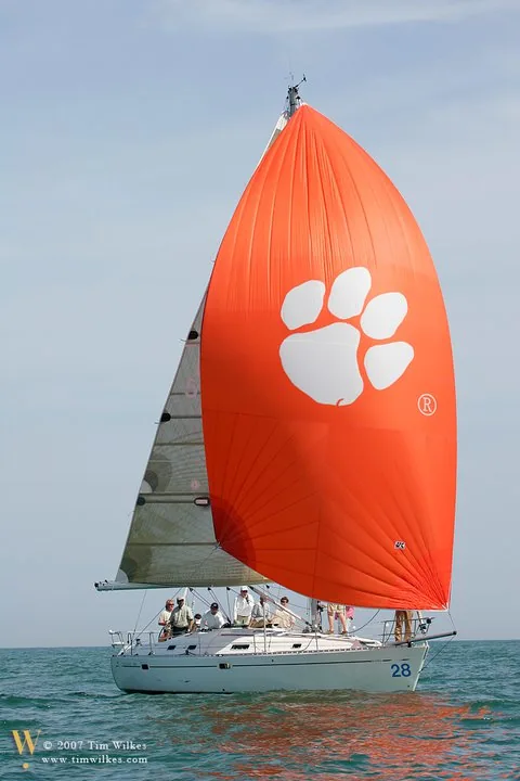Cruising yacht 28 running under a bright orange asymmetric spinnaker printed with a giant white paw print