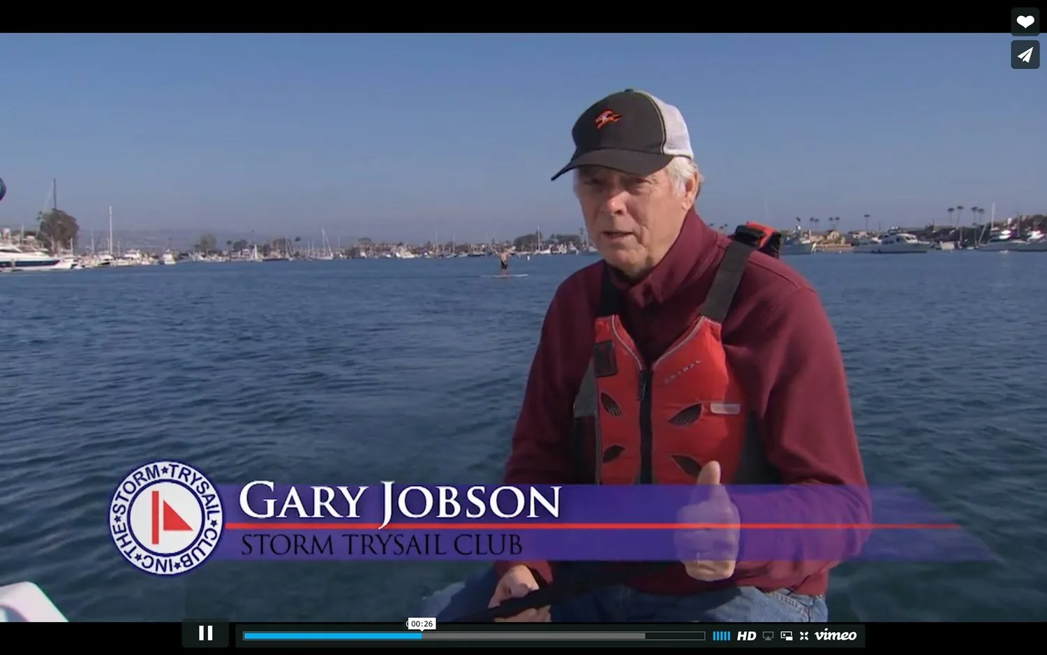 Video still of Gary Jobson in a red life jacket aboard a RIB in a harbour, Storm Trysail Club lower-third caption