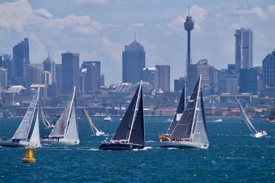 TRIPLE LINDY, dark blue hull, leading her class off the Sydney Hobart start with the Sydney skyline behind