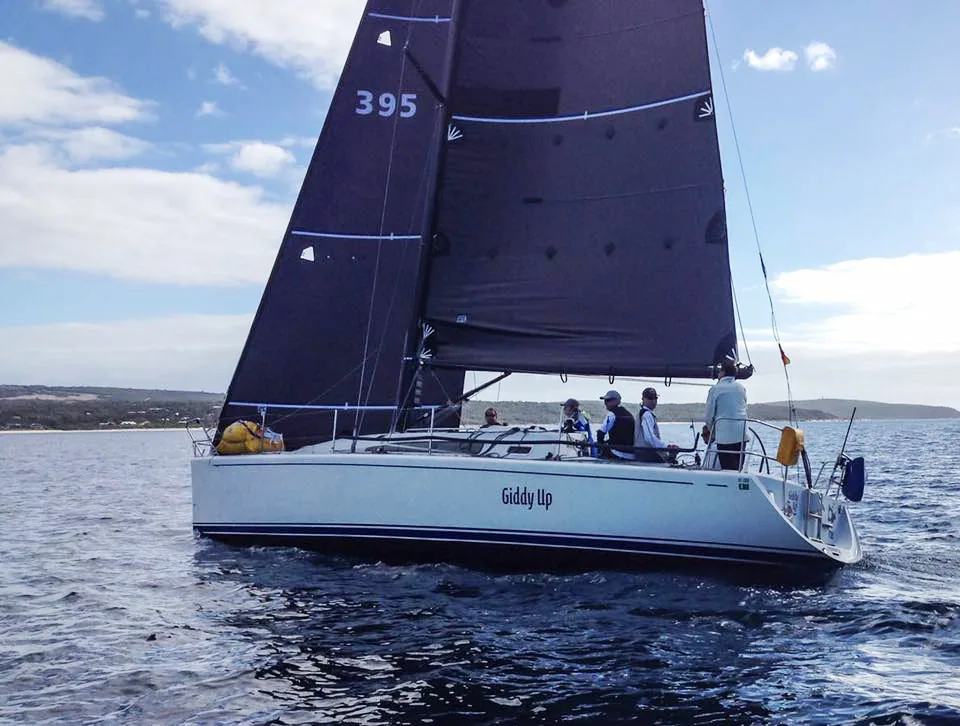 Farr 395 Giddy Up sailing under black Titanium mainsail and jib with five crew aboard, coastline behind