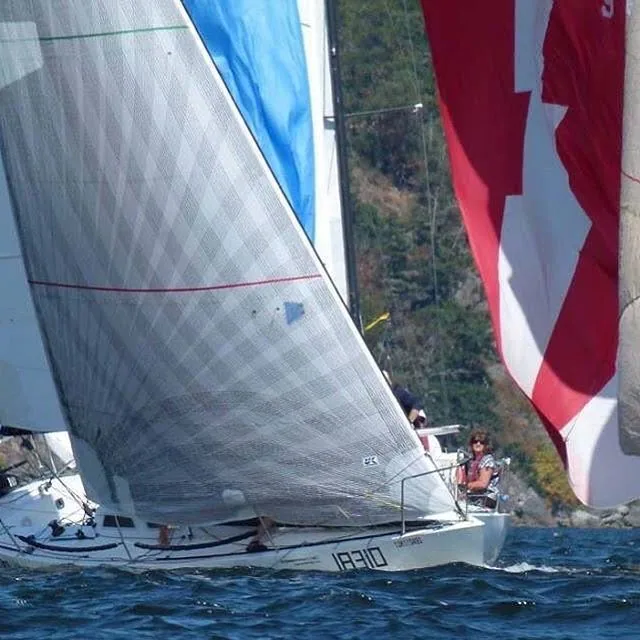 Olson 30 Beats Per Minute, sail number 18310, beating under a grey X-Drive® headsail with spinnakers astern