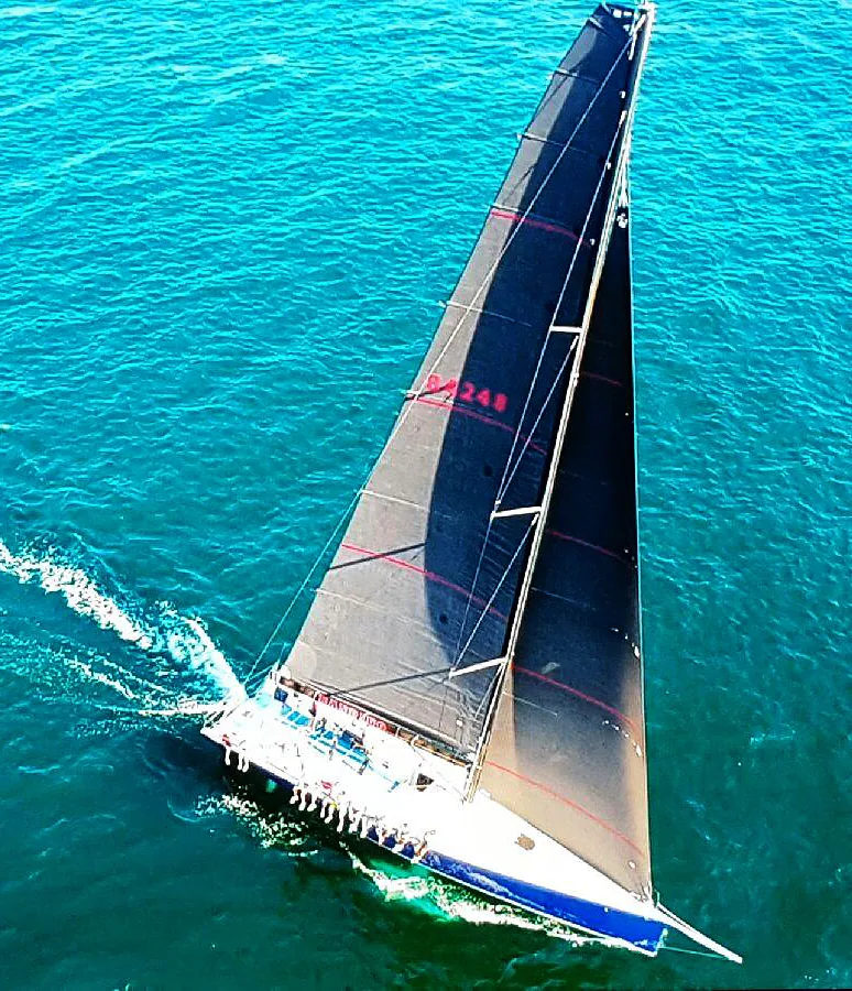 Aerial view of the Southern Cross 52 BANDIDO heeling under black Uni-Titanium mainsail and jib on turquoise water