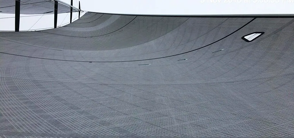 Grey laminate jib seen along its foot from the deck, a small clear window set near the tack