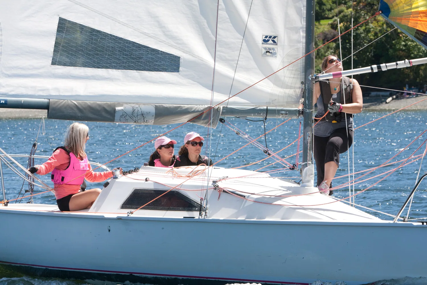 Four-woman crew in pink on a Martin 242 keelboat, one standing at the mast, UK Sailmakers logo on the mainsail