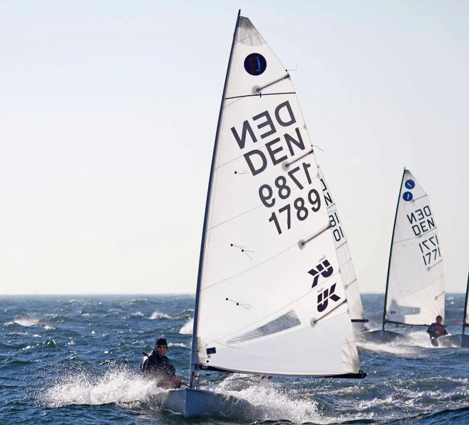 Europe dinghies DEN 1789 and DEN 1771 planing upwind in choppy water, UK Sailmakers logo on the mainsail