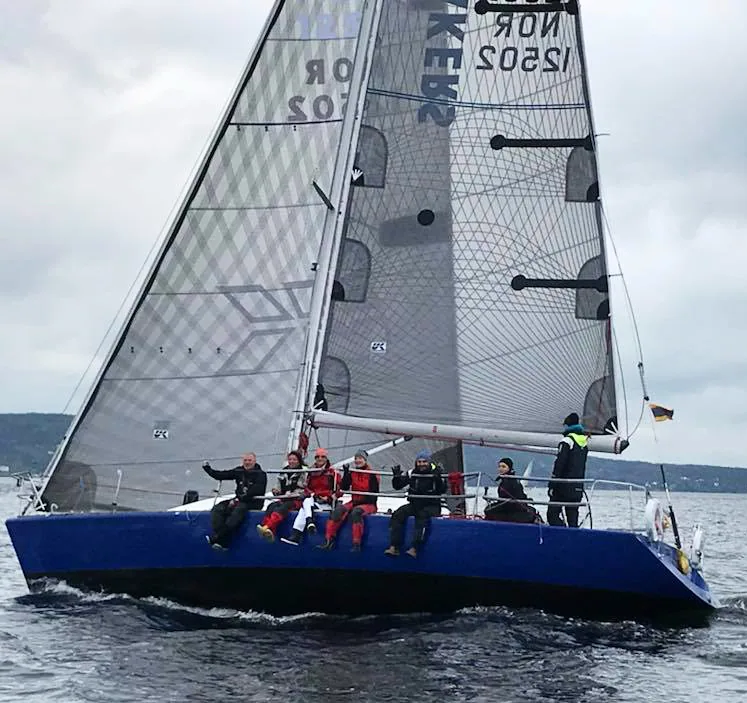 IMX 38 BRAVEHEART, NOR 12502, sailing upwind with a grey X-Drive® genoa and Tape-Drive mainsail, crew waving from the rail