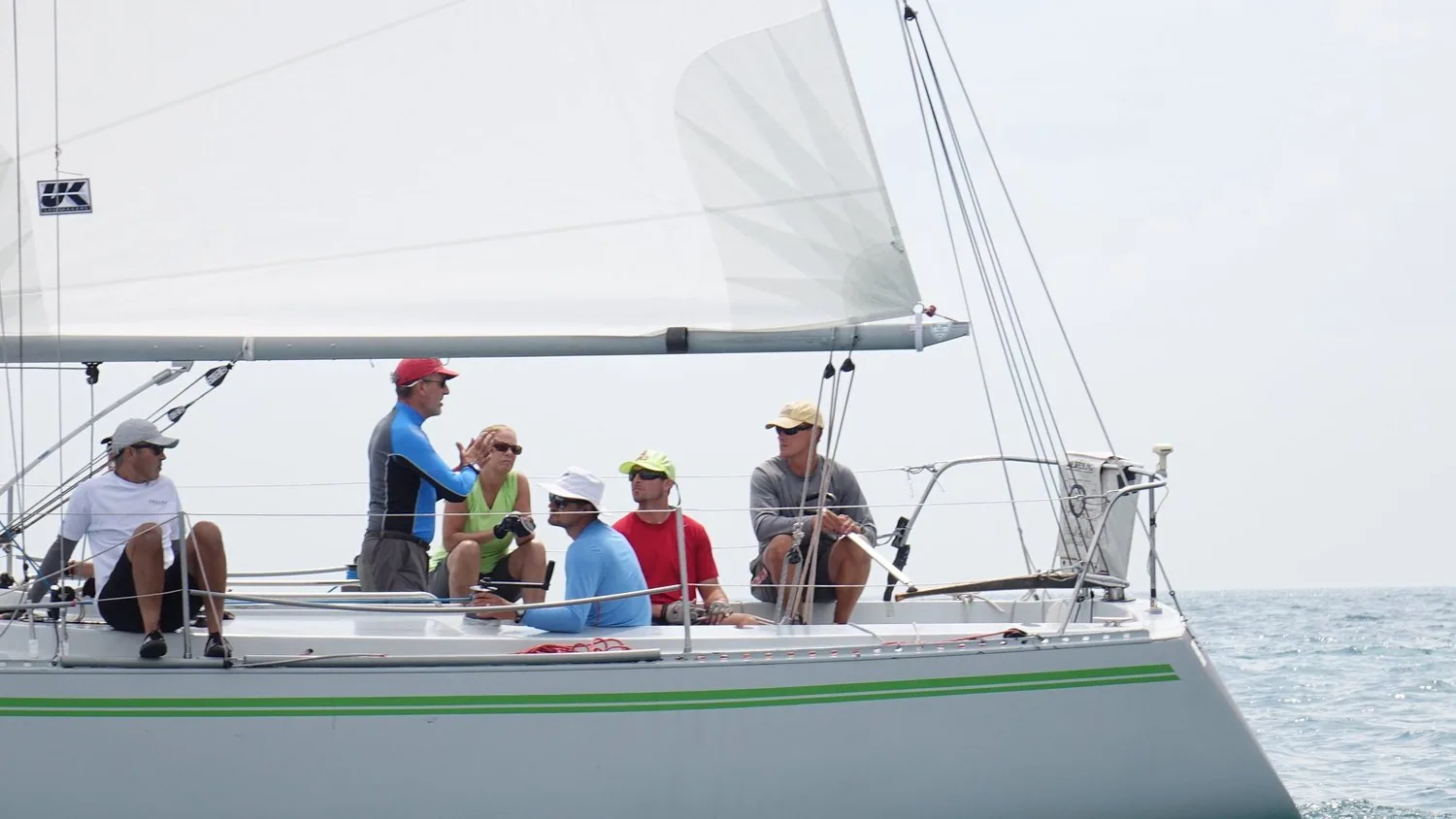 Tartan 10 ERICA with a green cove stripe and six crew in sun hats aboard, UK Sailmakers logo on the mainsail, light air