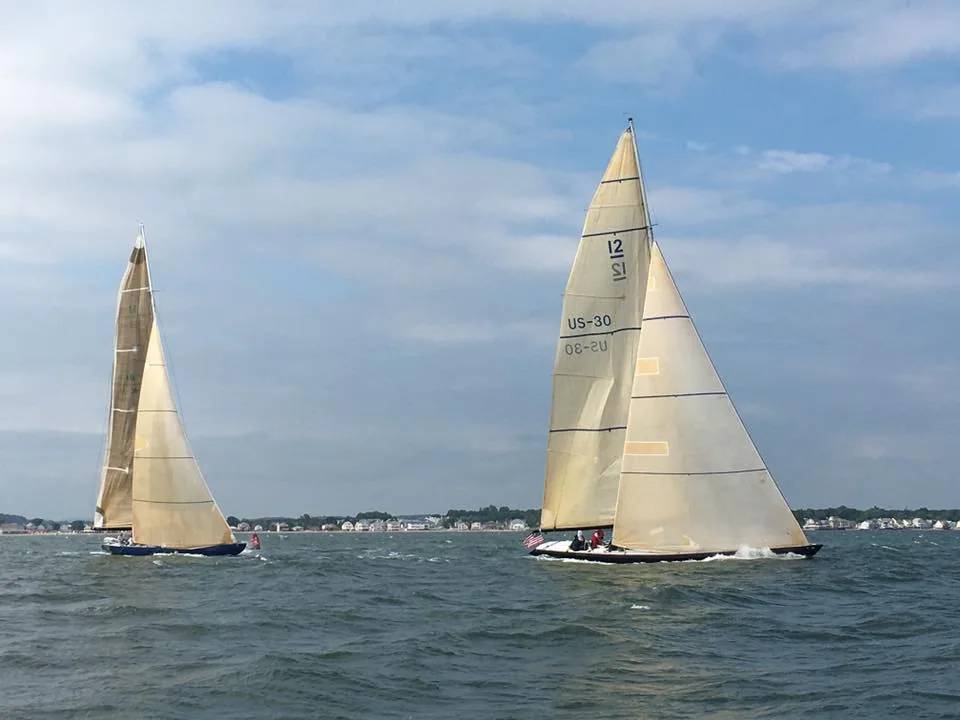 Two 12 Metres with cream-coloured sails approaching a leeward mark in light air, US-30 on the right, low shoreline behind