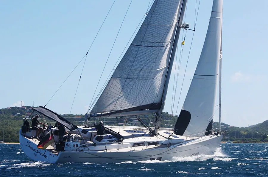 Hanse 575 SEASIDE beating upwind under grey mainsail and white genoa with a German flag off the stern