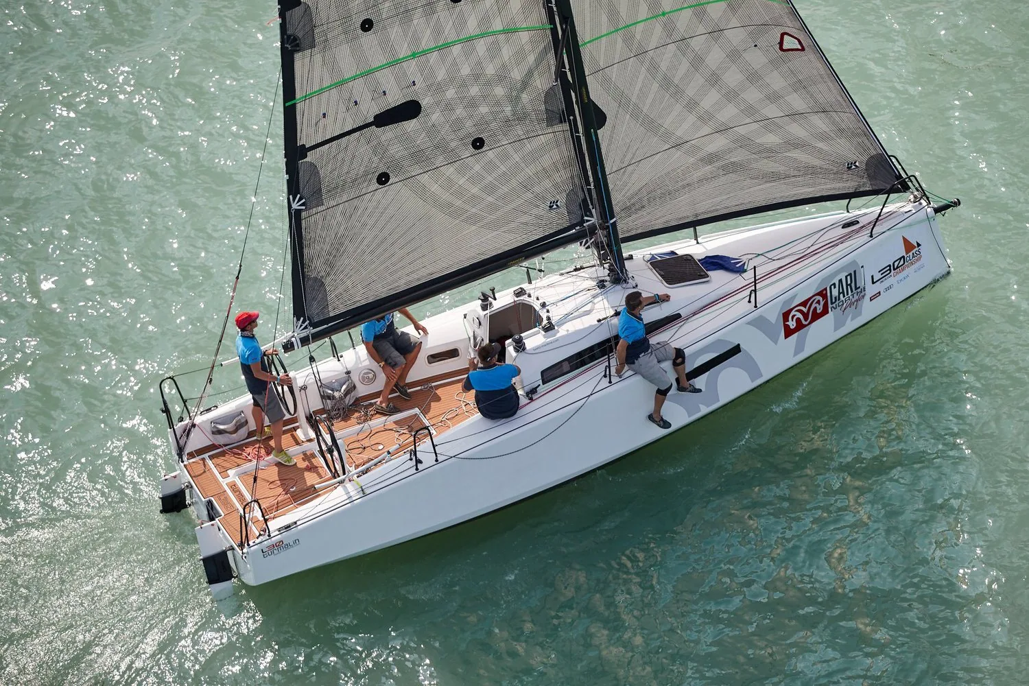 Overhead view of an L30 one-design sailing upwind under grey X-Drive® mainsail and genoa with four crew