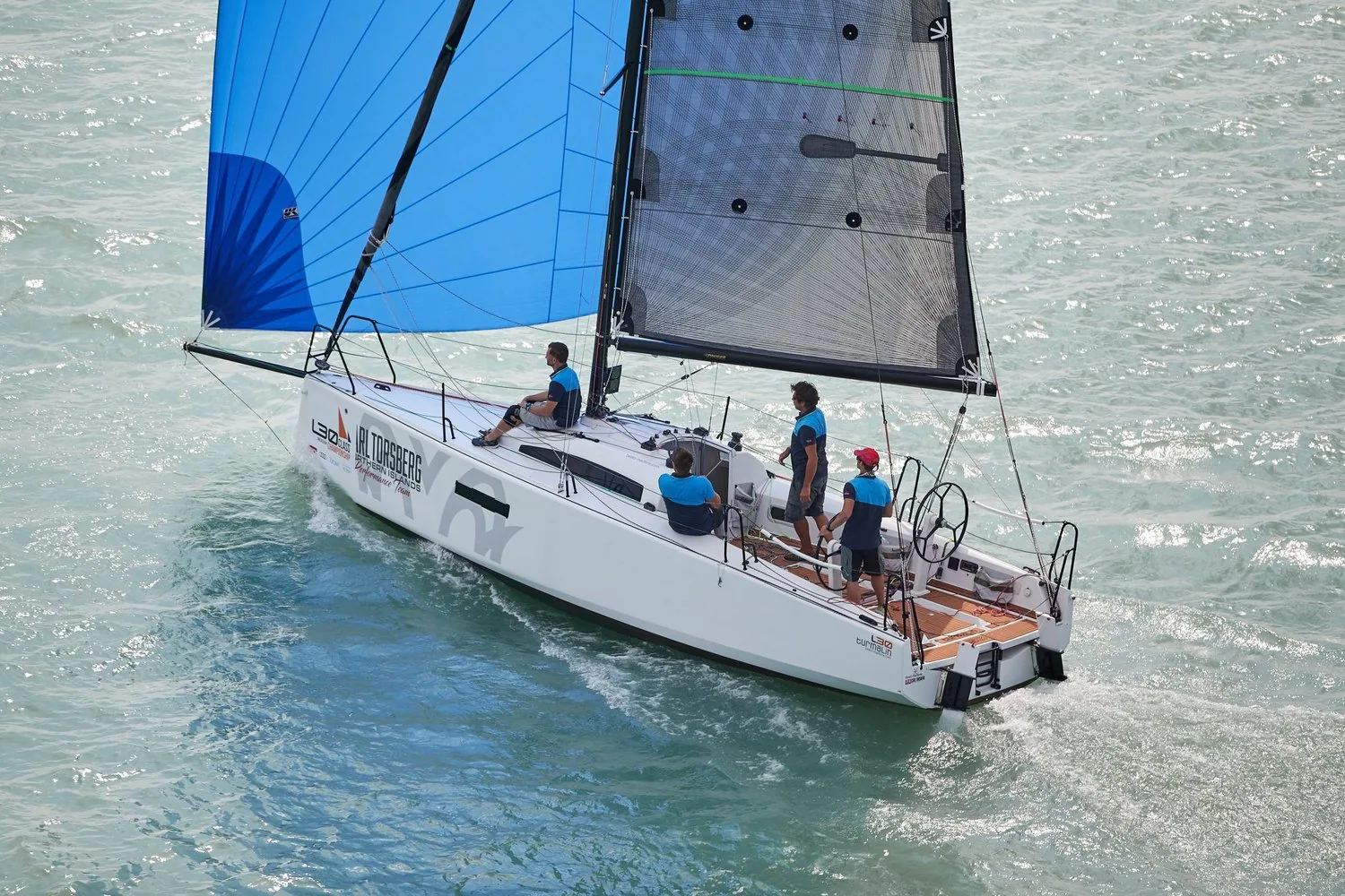 Aerial view of an L30 running under a blue asymmetric spinnaker and grey X-Drive® mainsail with four crew aboard
