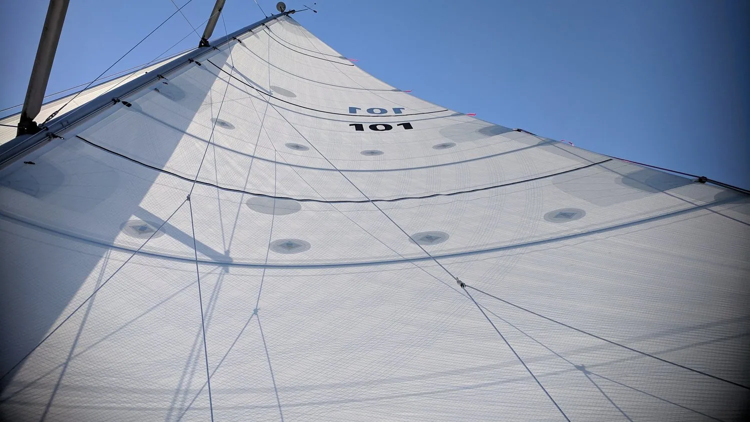 Looking up a white X-Drive® Endure mainsail, sail number 101, with load-path tapes fanning from the clew