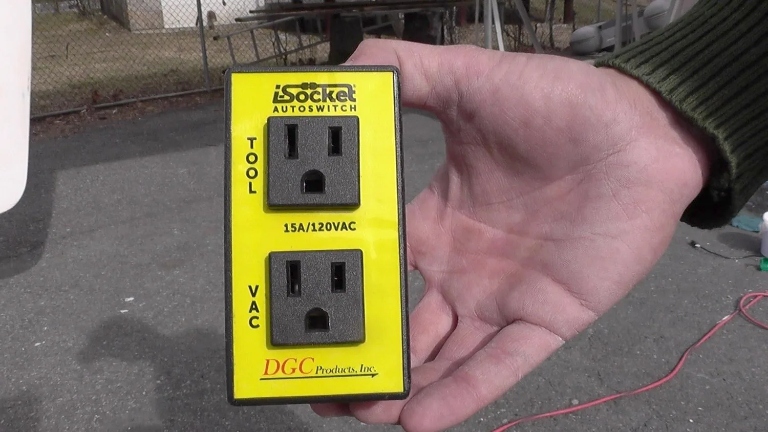 Hand holding a yellow iSocket Autoswitch with two outlets labelled Tool and Vac for auto-starting a shop vacuum