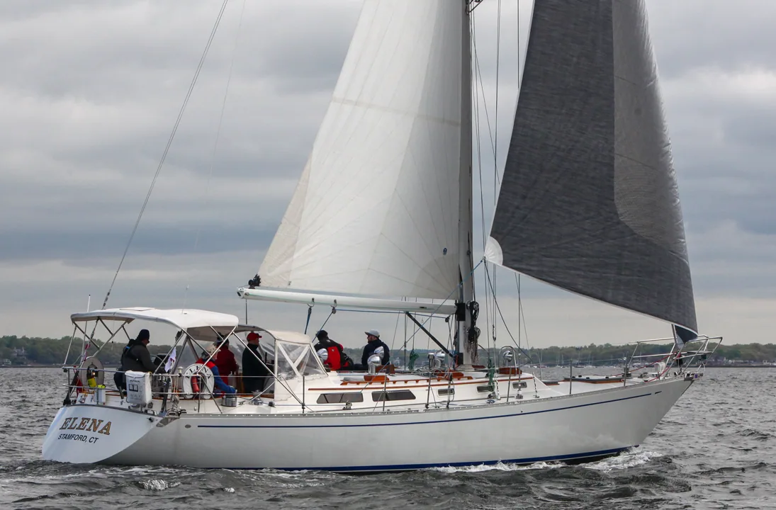 Alden 50 ELENA beating in grey conditions under white mainsail and grey genoa, crew in red jackets aft