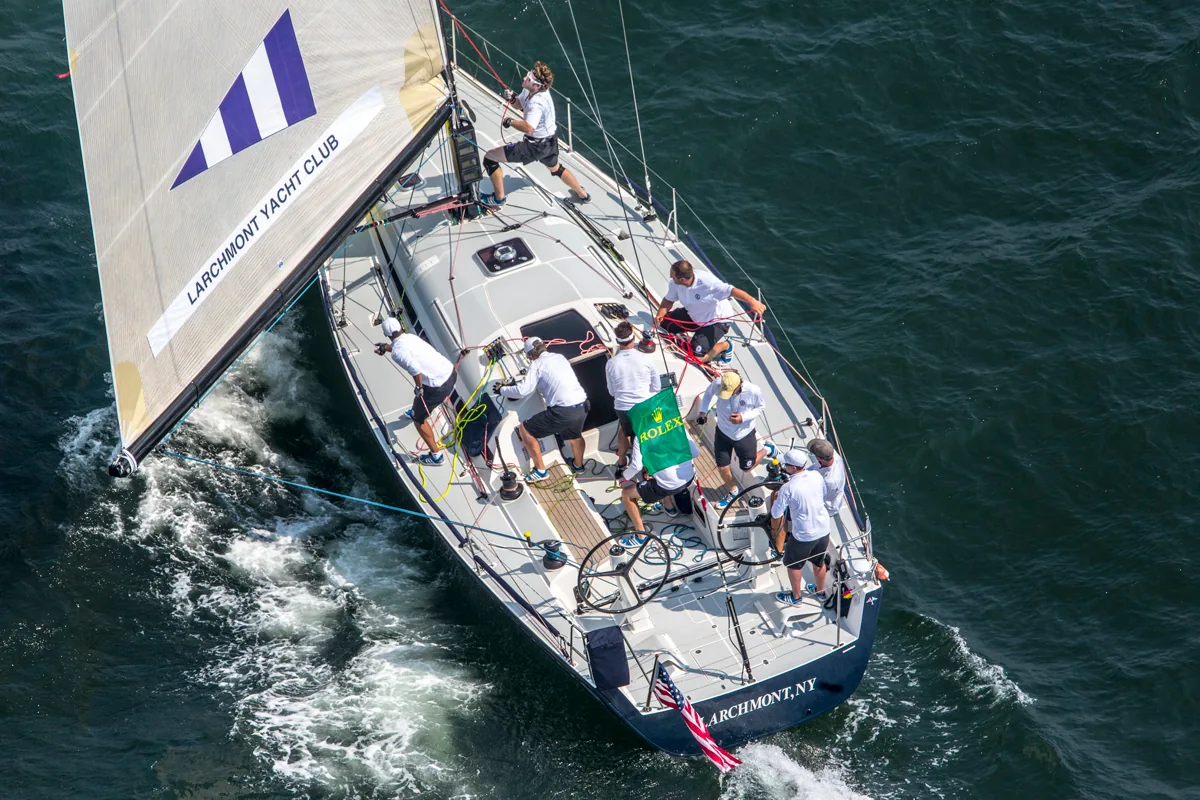 Overhead view of a Swan 42 crew in white shirts at work, a Larchmont Yacht Club spinnaker filling to leeward