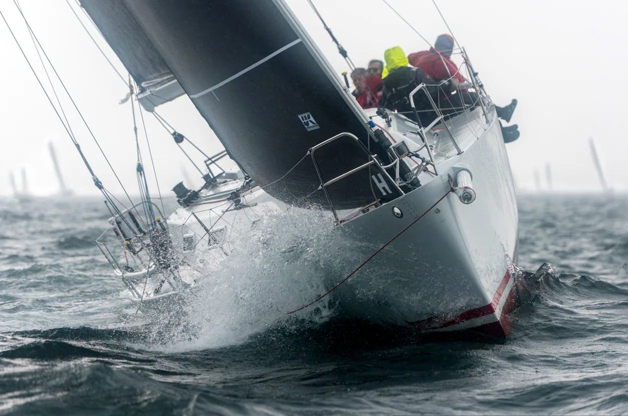 Adam Loory's custom 40-footer SOULMATES pounding upwind bow-on into a wave, spray flying, dark grey sails
