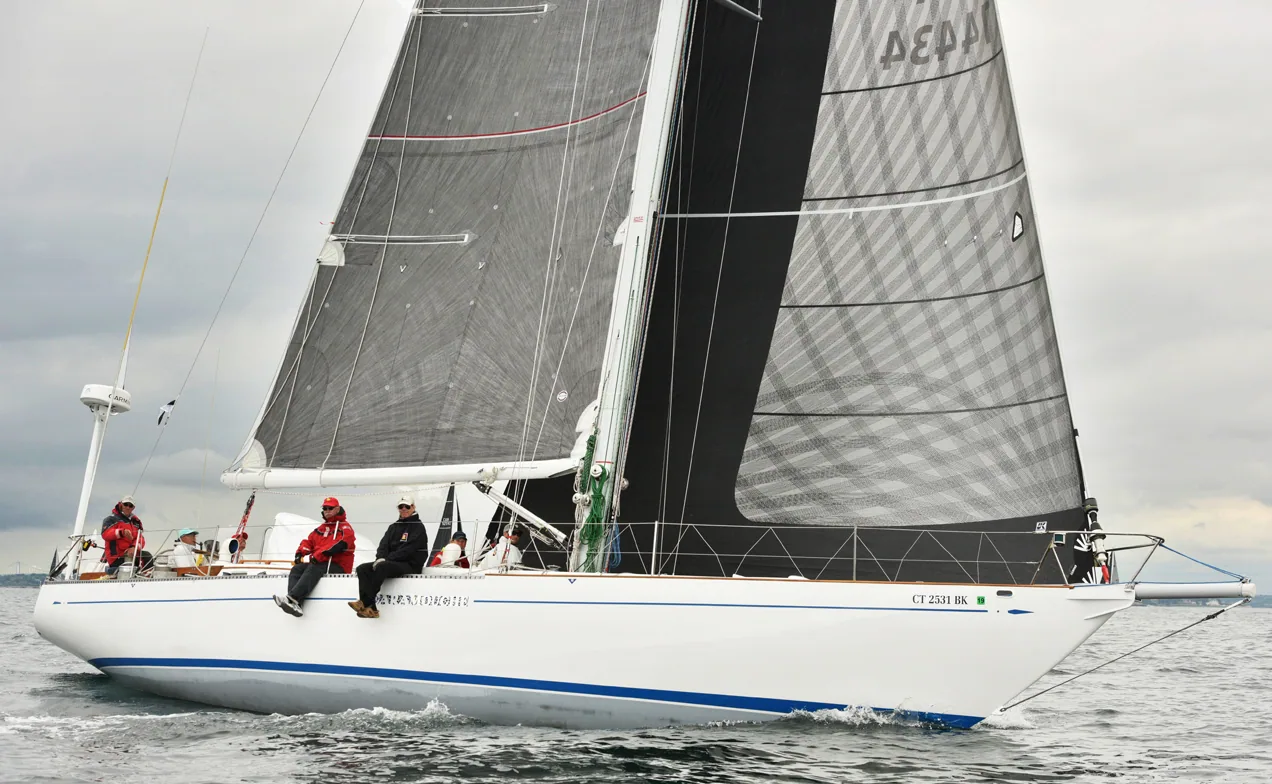 HIRO MARU beating upwind under grey laminate mainsail and genoa, crew in red jackets hiked on the rail