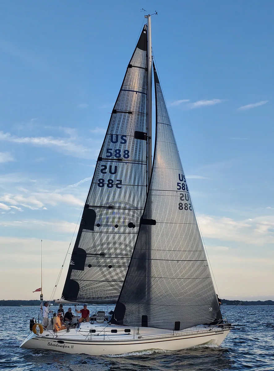 SHADOWFOX II, US 588, under black X-Drive® mainsail and genoa in evening light, crew relaxing in the cockpit