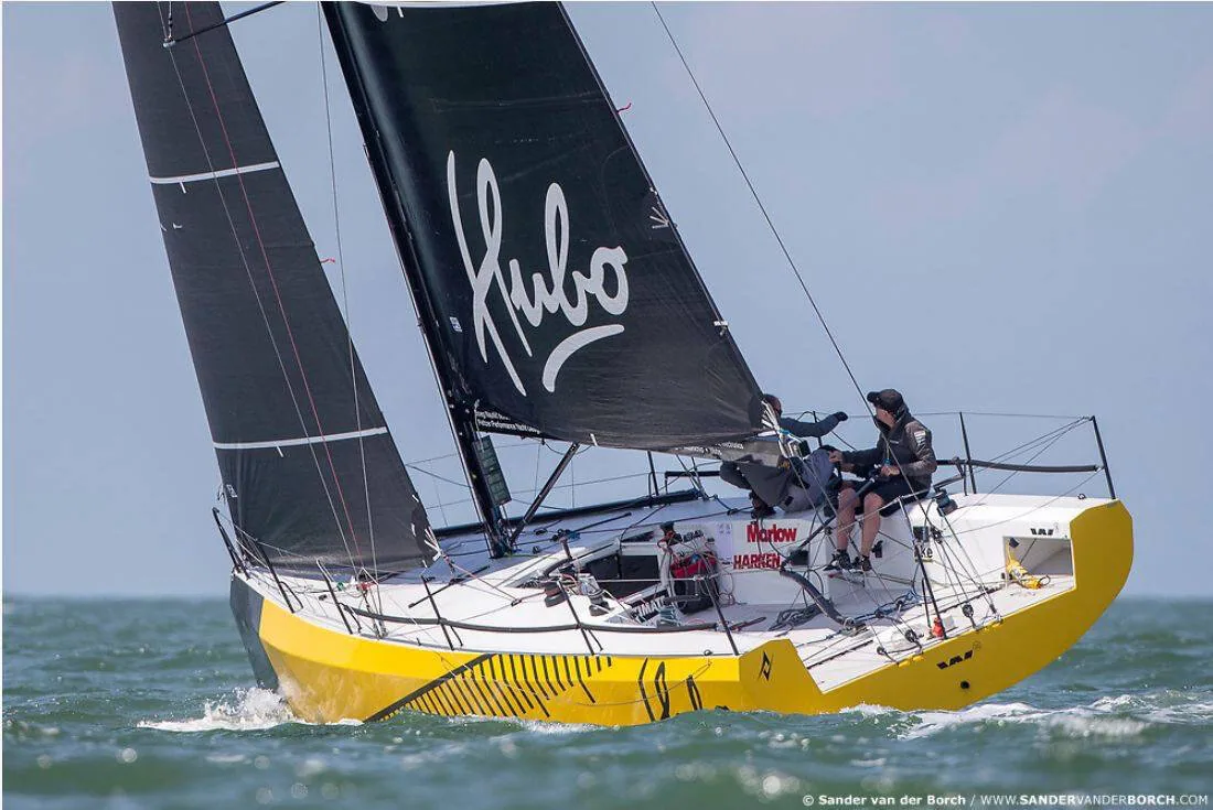 Yellow-hulled HUBO reaching under black mainsail and jib with Hubo script logo, two crew sailing doublehanded