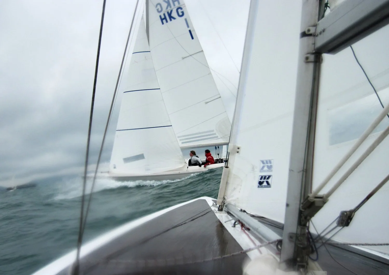 Onboard view of one Dragon crossing close ahead of another, HKG sail number and a UK Sailmakers logo on the jib