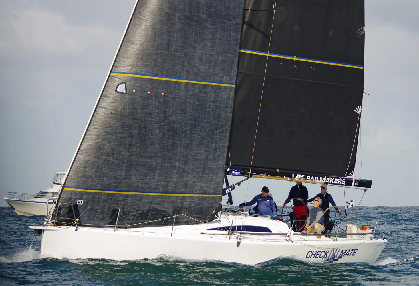 King 40 CHECKMATE beating upwind under grey laminate mainsail and genoa, UK Sailmakers boom cover, crew of four aft