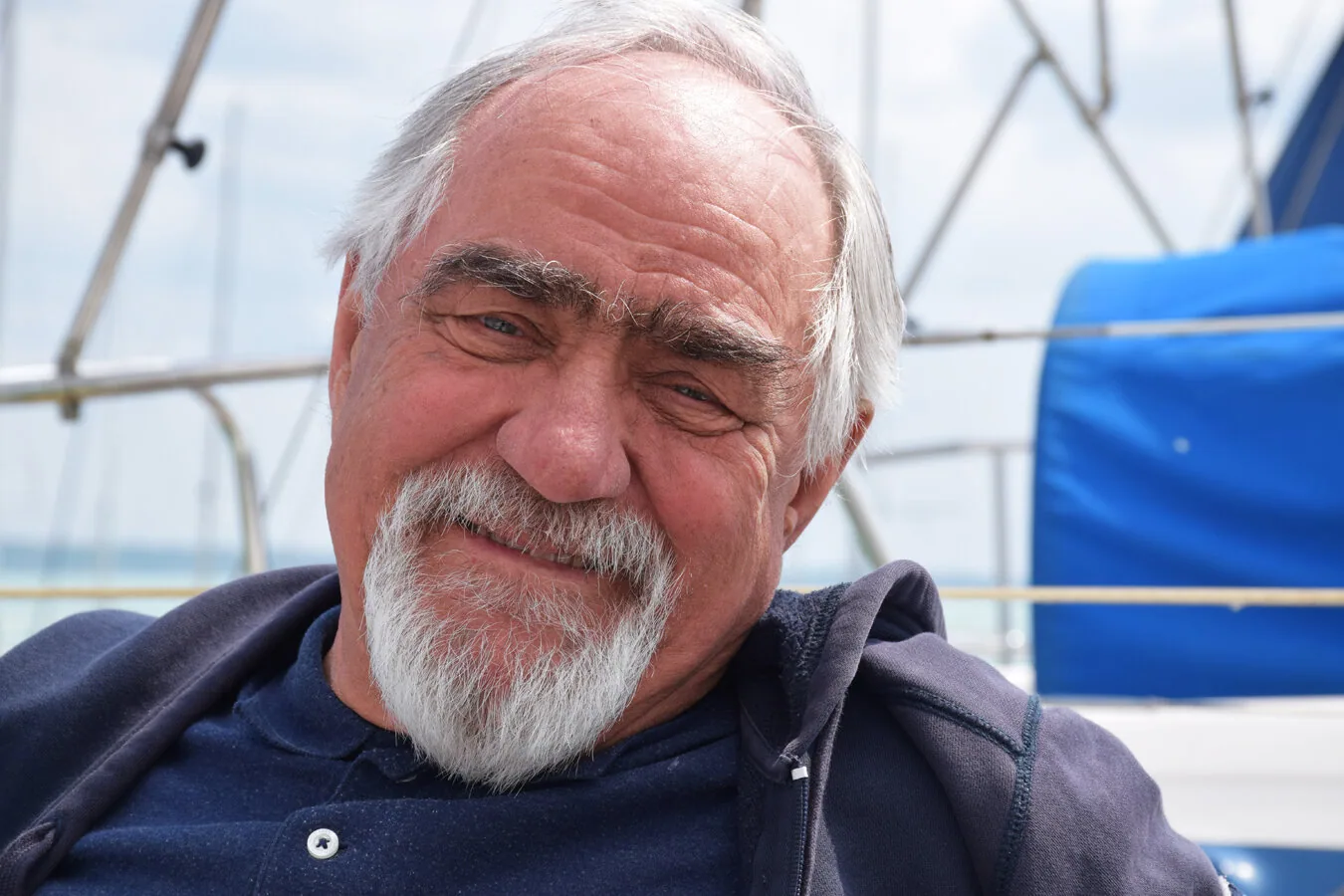 Tamas Bakos of UK Sailmakers Hungary, grey-haired with a white goatee, smiling in the cockpit of a sailboat