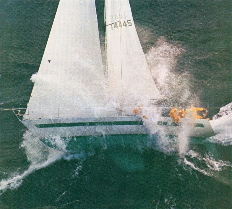 One-Tonner LOVE MACHINE burying her bow in a wall of spray, sail number 14445, crew in orange gear on the foredeck