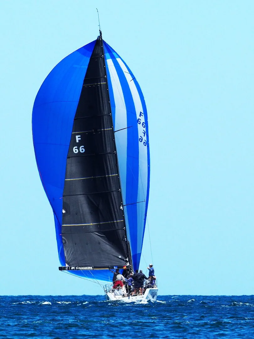 King 40 CHECKMATE running deep under a blue and white A2 asymmetric spinnaker projected to windward, black mainsail