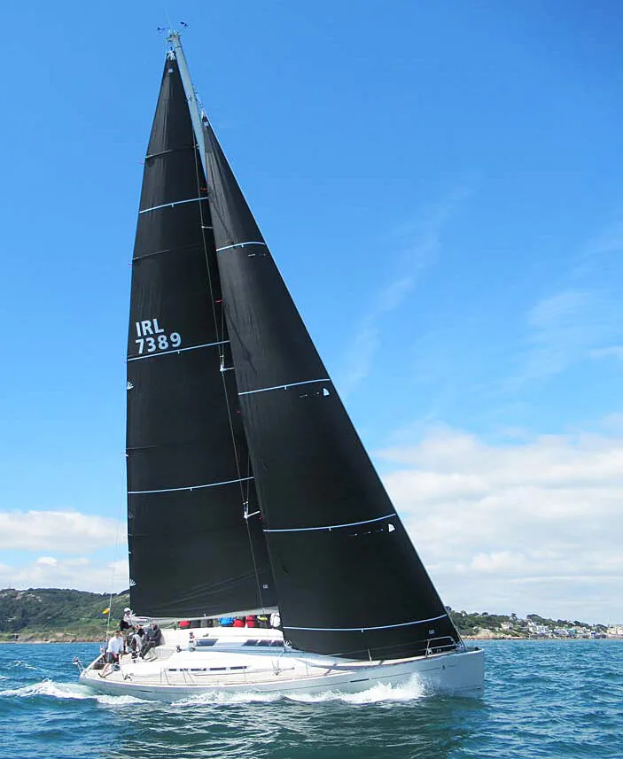 Beneteau First 50 MERMAID, sail number IRL 7389, close-hauled under black laminate main and genoa off a green shoreline