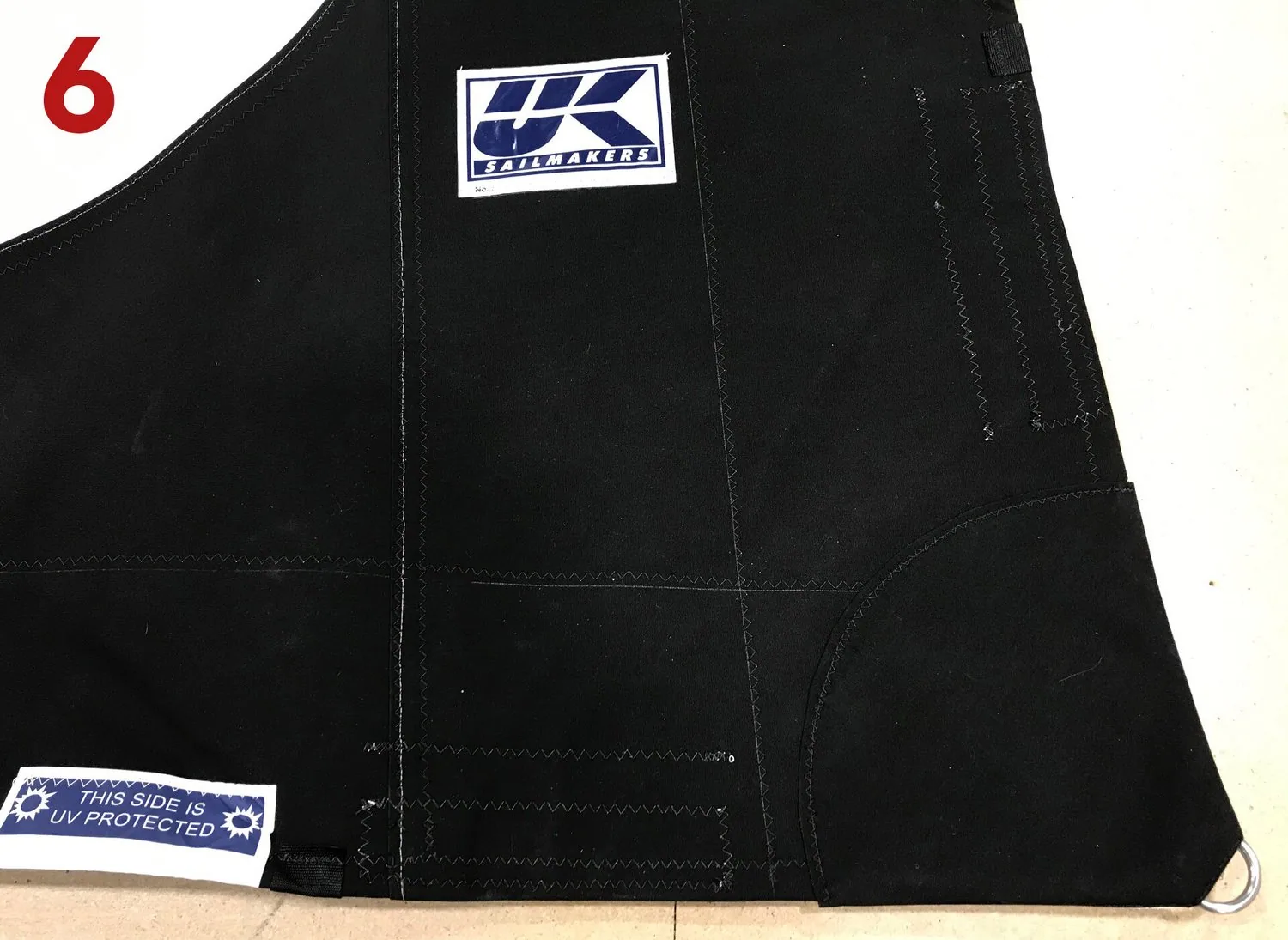 Black UV cover patch sewn over the clew reinforcement of a genoa, with a UK Sailmakers label, labelled 6