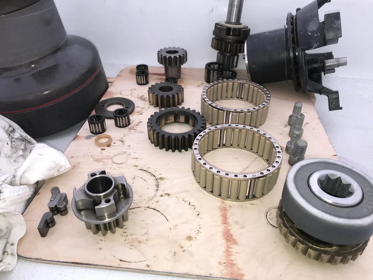 Disassembled sailboat winch: drum, gears, roller bearings and pawls laid out on cardboard for cleaning