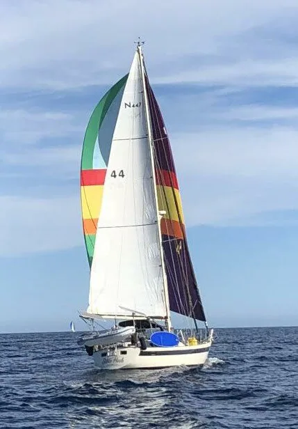 Silver Heels running downwind under a rainbow spinnaker and a maroon-and-gold striped sail, main marked N447 44