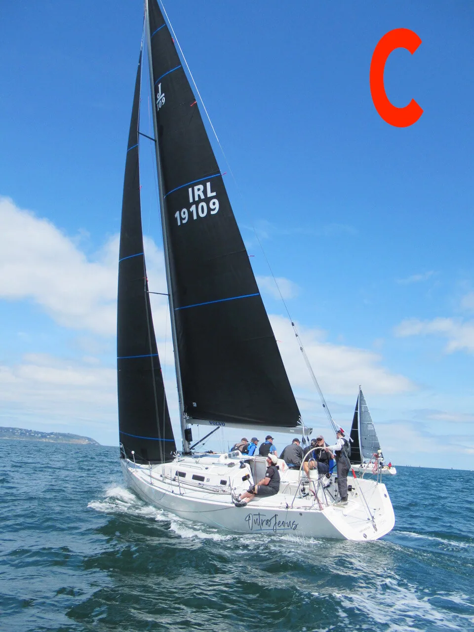 Photo C: sloop IRL 19109 sailing upwind under black mainsail and jib with blue trim stripes, crew in the cockpit