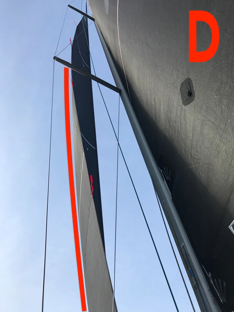 Photo D: looking up a black jib from the deck with a red line traced along its edge, mast on the right