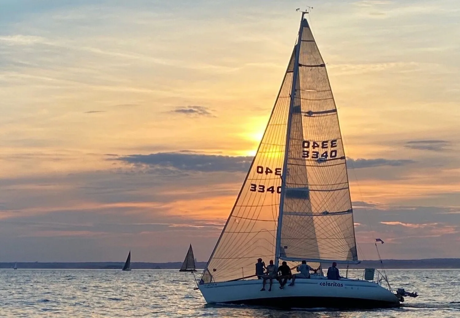 CELERITAS, sail number 3340, sailing at sunset under tan vintage UK Sailmakers sails, crew on the rail