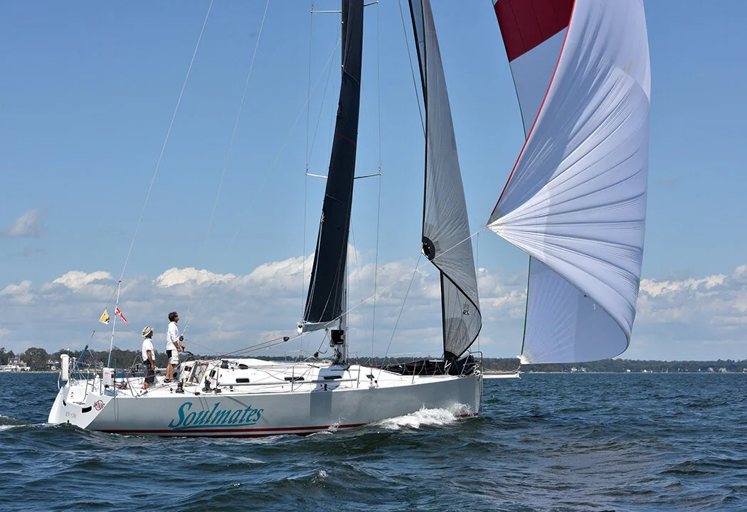 SOULMATES under black upwind sails flying a red-and-white asymmetric spinnaker, two crew aboard