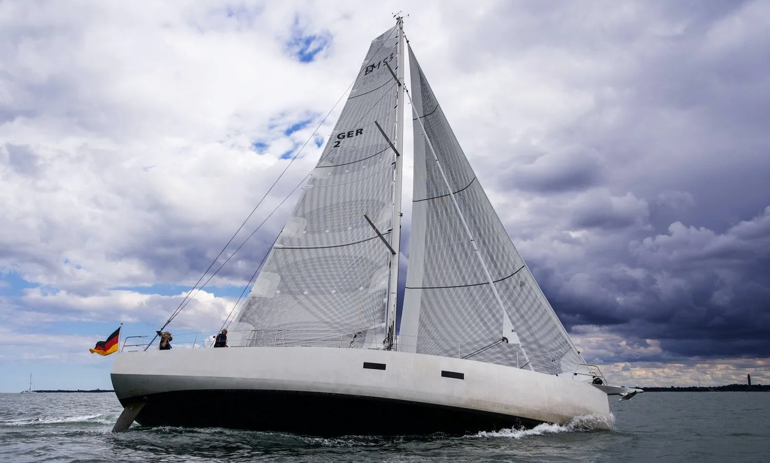 Bow-on view of the grey Berckemeyer 53 under grey X-Drive® Carbon sails beneath dark storm clouds