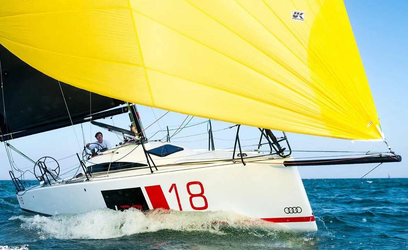 L30 One-Design number 18 reaching under a yellow UK Sailmakers spinnaker and black mainsail