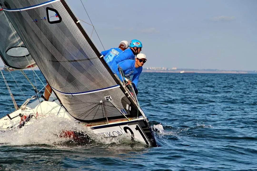 Platu 25 heeled hard upwind under grey UK Sailmakers sails, crew in blue hiking as spray flies