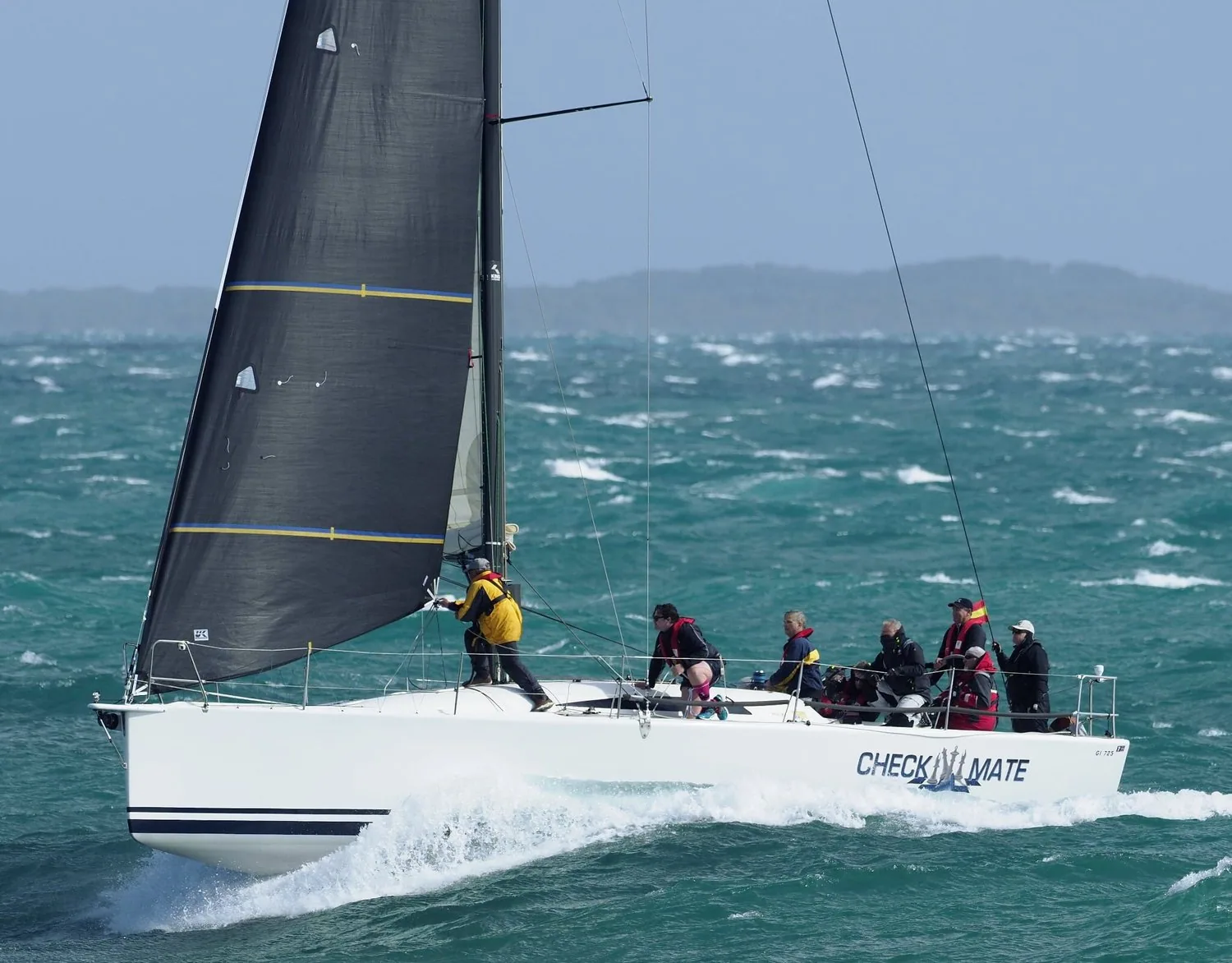 King 40 CHECKMATE surfing downwind in heavy air, bow lifting clear, crew in foul-weather gear aft