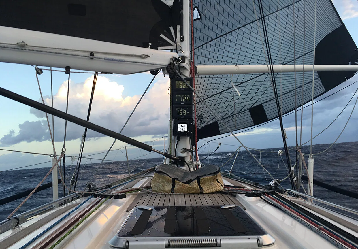 On deck of TRIPLE LINDY with a black No. 4 jib poled out to windward and a mast instrument display