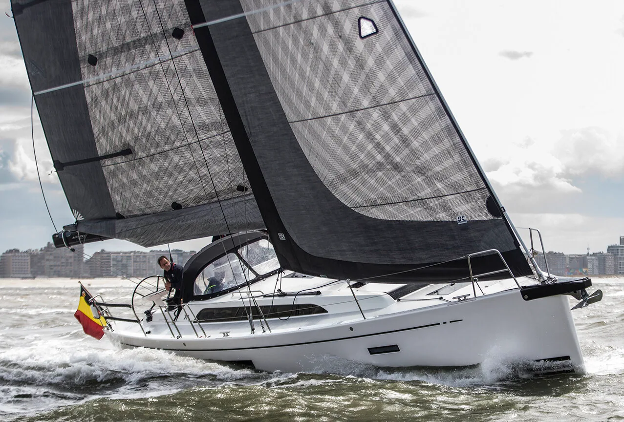 X4.0 heeled upwind under grey X-Drive® carbon mainsail and genoa with partial taffeta, Belgian flag at the stern