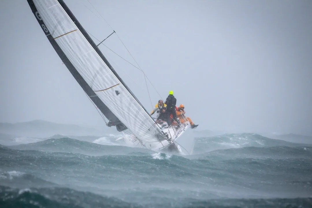 J/125 JACK KNIFE heeled hard in grey squally seas with crew on the rail at the IRC Regatta, Pwllheli
