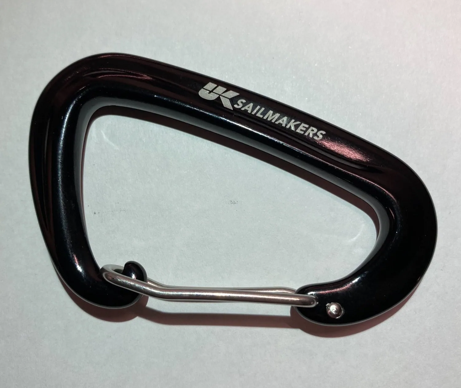 Black anodised carabiner engraved with the UK Sailmakers logo, on a white background