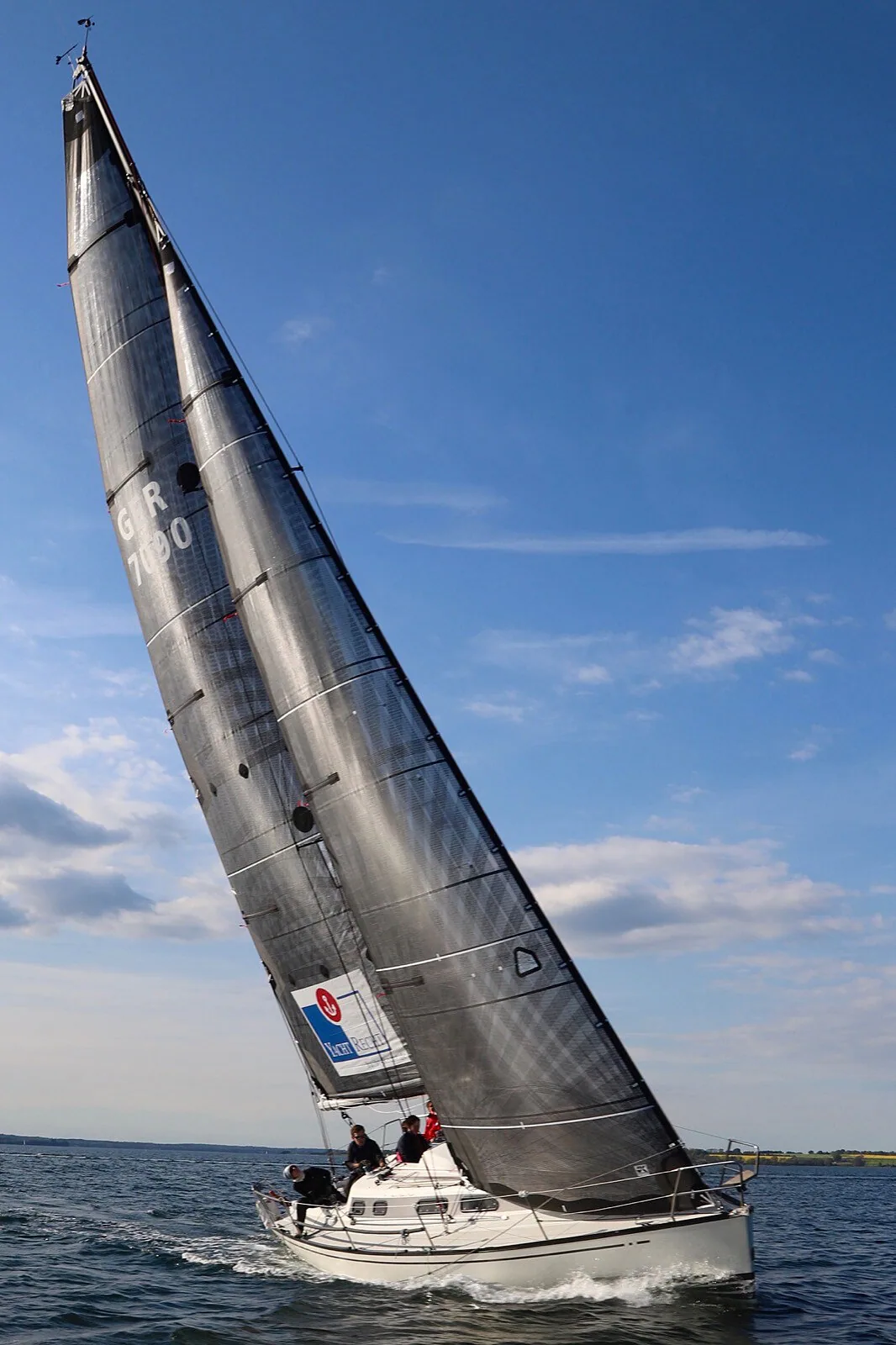 X-332 SOPHUS heeled under a black X-Drive® wider-head mainsail and jib, sail number GER 7090, three crew aft
